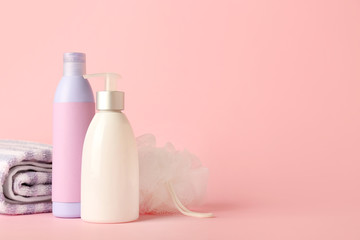 Shower gels, towels and loofah on color background
