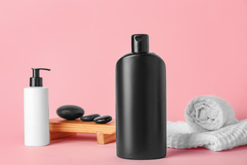 Shower gels, spa stones and towels on color background