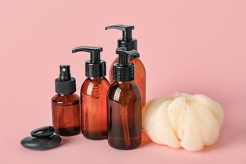 Shower gels and loofah on color background