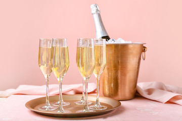 Bucket with ice and champagne on color background