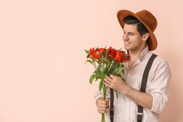 Handsome man with bouquet of flowers on color background