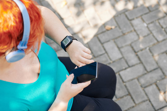 Active plus size woman checking health application on her smartwatch and synchronizing with smartphone