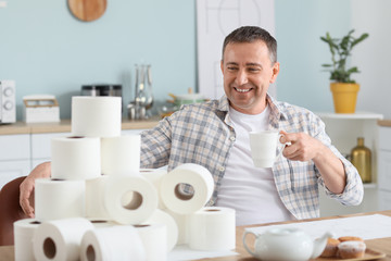 Mature man with heap of toilet paper at home. Concept of coronavirus epidemic