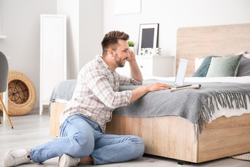 Young man with laptop working at home