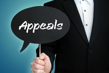 Appeals. Lawyer in suit holds speech bubble at camera. The term Appeals is in the sign. Symbol for law, justice, judgement