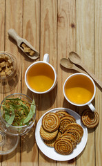 Alternative tea with linden in white cup of tea and cookies with wooden spoons on a brown wooden background. Healthcare tea, alternative medcine. Copy spase.