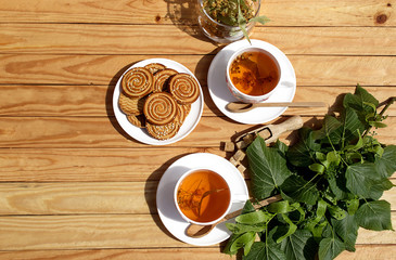 Alternative tea with linden in white cup of tea and cookies with wooden spoons on a brown wooden...