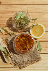 Alternative tea with linden in glasses of tea and lemon, wooden spoon on a brown wooden background. Healthcare tea, alternative medcine. Close up