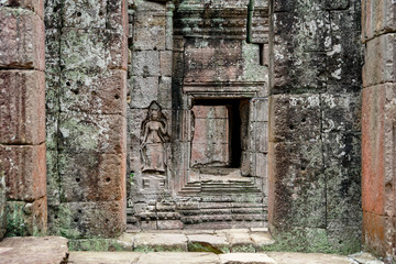 Fototapeta na wymiar Ta Som, Angkor Wat Temple in Cambodia, Big Circle. window opening and carved image of a goddess, laterite stone background