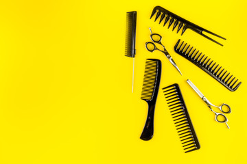 Combs, hairbrush, scissors on yellow desk from above copy space