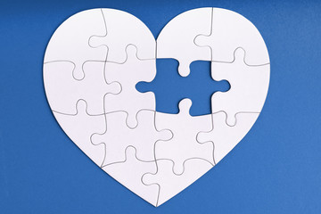 Love, charity, donation, helping concept. Missing piece of jigsaw puzzle in heart shape on blue....