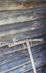 Old wooden rake on the background of the log wall of the old village house
