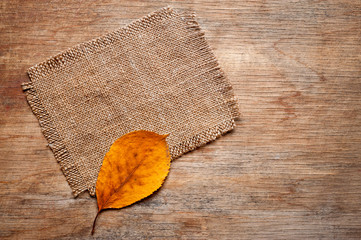 .A canvas napkin and tree leaves lying on a wooden surface. Background for fall and natural objects.