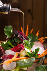 Vegetable salad with olive oil dressing. Olive oil stream and healthy fresh vegetable salad.