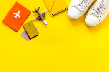 Tavelling background - airplane, shoes, notebook, passport - on yellow table from above copy space