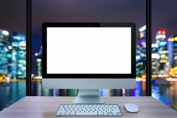 Fototapeta premium Computer monitor, mouse, keyboard on table with cityscape background.
