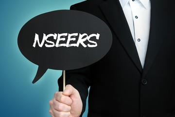 NSEERS. Lawyer in suit holds speech bubble at camera. The term NSEERS is in the sign. Symbol for law, justice, judgement