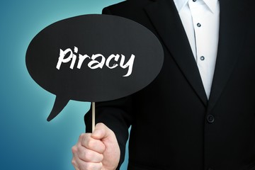 Piracy. Lawyer in suit holds speech bubble at camera. The term Piracy is in the sign. Symbol for law, justice, judgement
