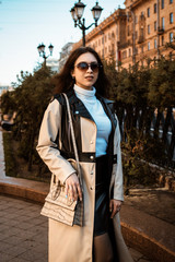 Young stylish woman at city. Fashion model girl in trendy coat . Female fashion and lifestyle. In a black and white coat, white sweater, black blouse. In sunglasses