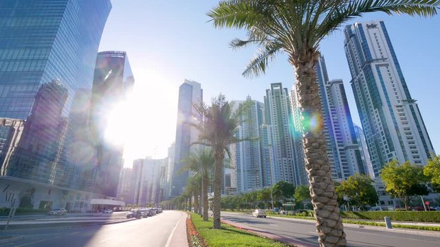 Bright white sun shines between tall skyscrapers in downtown tropical Dubai