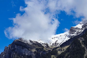 swiss mountain peak with blue sky and clouds.