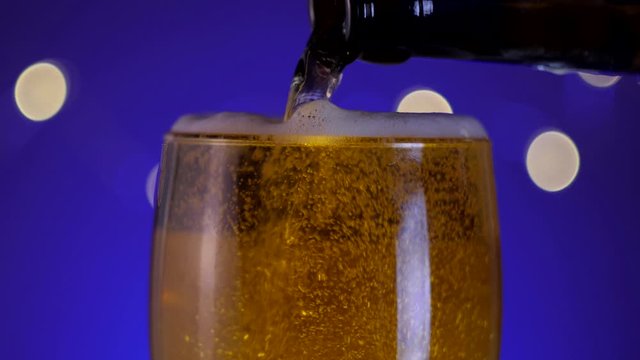 pouring lager beer into glass with bubbless and foam closeup