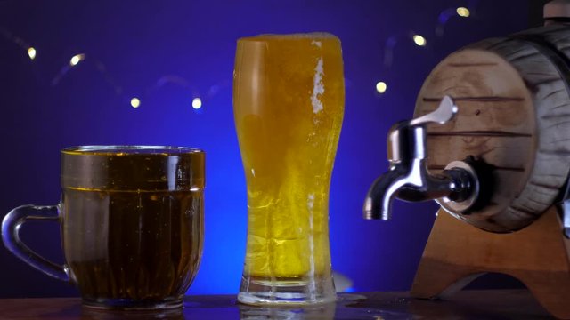 glass of beer with barrel and a mug on blue background