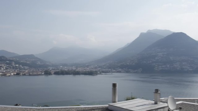 Fast pan over the lake Lugano and the city of Lugano from Paradiso on a cloudy day during summer with monte bre in the background, wider