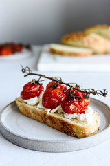 Tomato confit and goat cheese bruschetta on grey concrete table. Selective focus