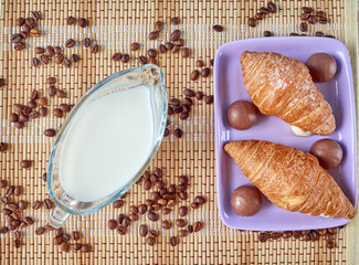 Glass mug with kefir and a plate with croissants and chocolates. Continental breakfast. Top view