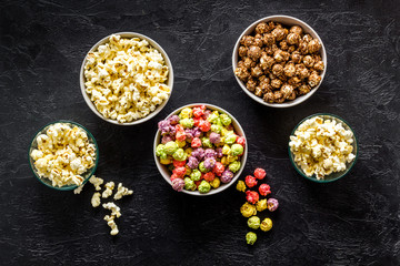 Obraz na płótnie Canvas Colored popcorn in bowl on black background top view