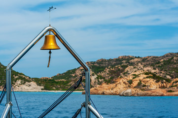 A view of the stern of the ship with in the background the blue sea and the vegetation of the rocks of the island on a sunny summer day, in Sardinia Italy
