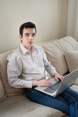 Young man sitting on sofat and using laptop at home