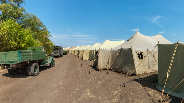 A big military World War II soviet tent camp with old trucks on a road