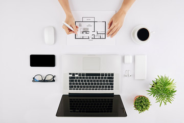 Flatlay of woman sitting at office table and working on design of apartment