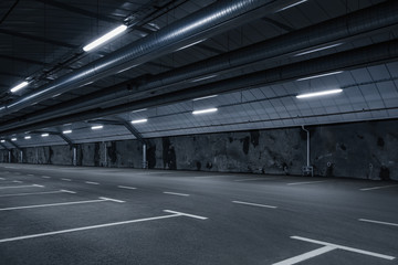 Sci fi looking empty, dark and moody underground parking lot with fluorescent lights on.  Long hall