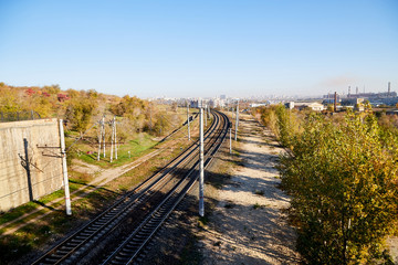 Fototapeta na wymiar View on railway from high place and trees arround in summer or autumn day. Nice lanscape with city and nature