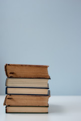 A simple composition of several old books on a white modern table with light gray background, back to school, education.