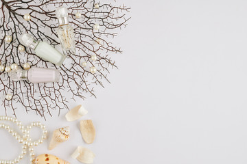 Small beautiful bottles with sweet fresh fragrances on tree branches with pearls and shells
