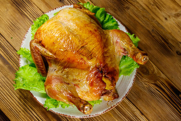 Baked whole chicken on a wooden table. Top view