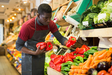 Obraz premium Sprzedawca układa warzywa i owoce na ladzie