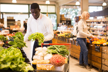 Obraz premium Man looking for vegetables in grocery store