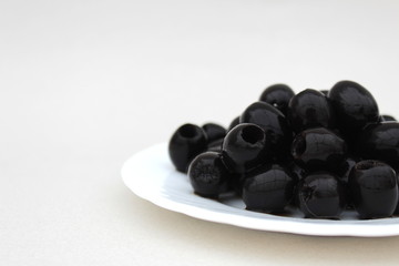 Black olives in a white plate on a gray background