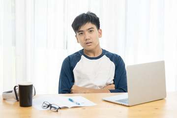 Asian teenager using laptop for home schooling concept during corona virus, crossed arms and looking at camera.