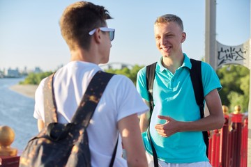 Outdoor portrait of two friends boys teenagers 15, 16 years old, talking laughing