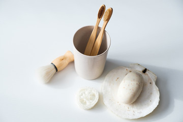 Set of eco friendly natural bathroom accessories on white background. Top view biodegradable bamboo toothbrushes, shaving brush, loofah, organic soap. Zero waste, sustainable lifestyle concept