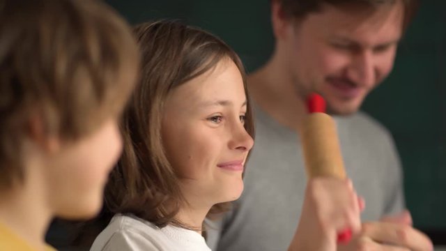 Children cooks pizza. Boy and girl having fun with father. Prepering ingredients for pizza. Dad gives children rolling pins for dough