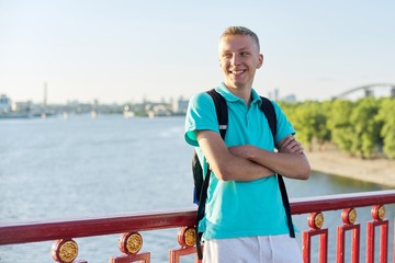 Outdoor portrait of smiling teenage boy 15, 16 years old with arms crossed
