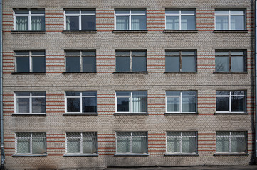Facade of the Soviet panel grey with orange old building with windows. Typical school, hospital building made in USSR.