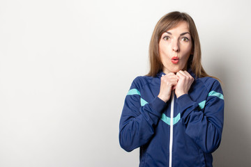 surprised young woman in a 90s sports jacket on a light background. Model looks away. Trendy sport...